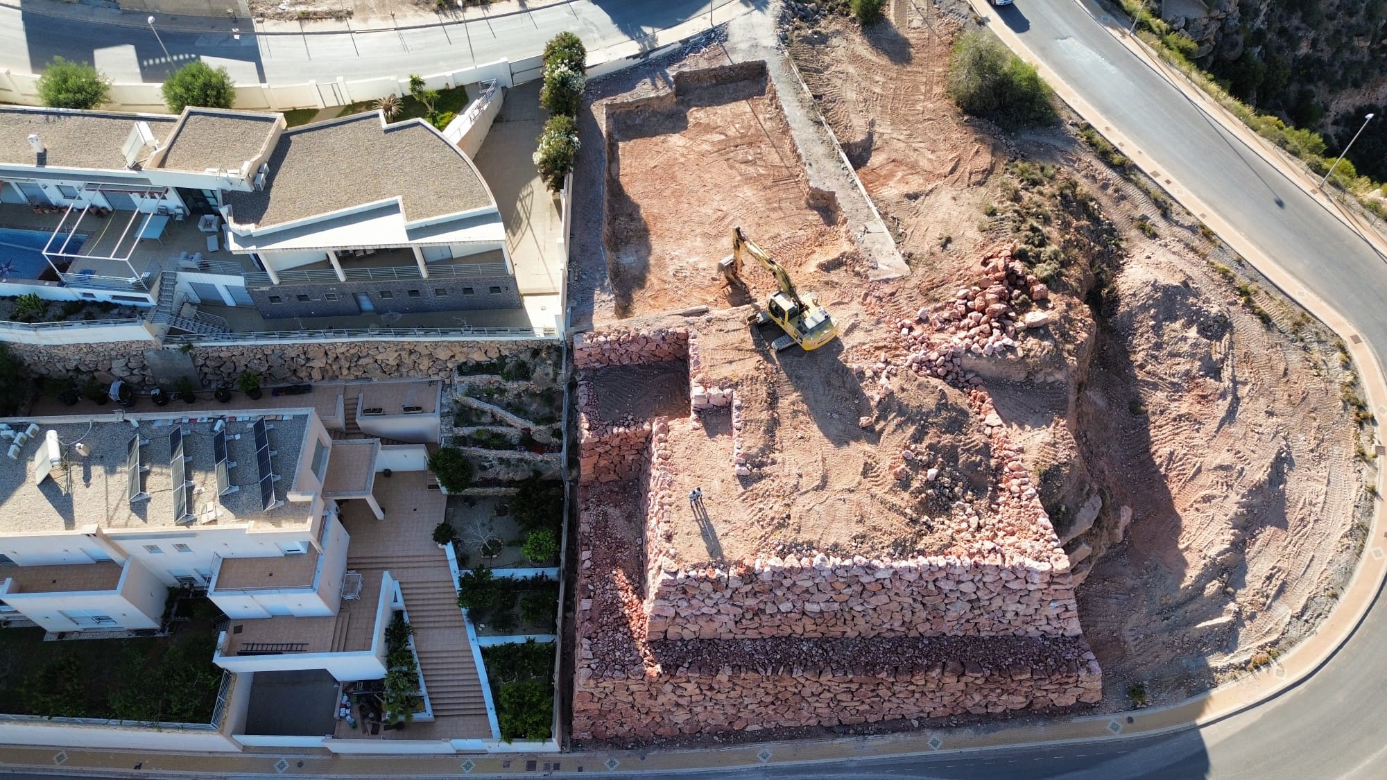 Detalle de los muros de escollera y excavadora trabajando en el terreno