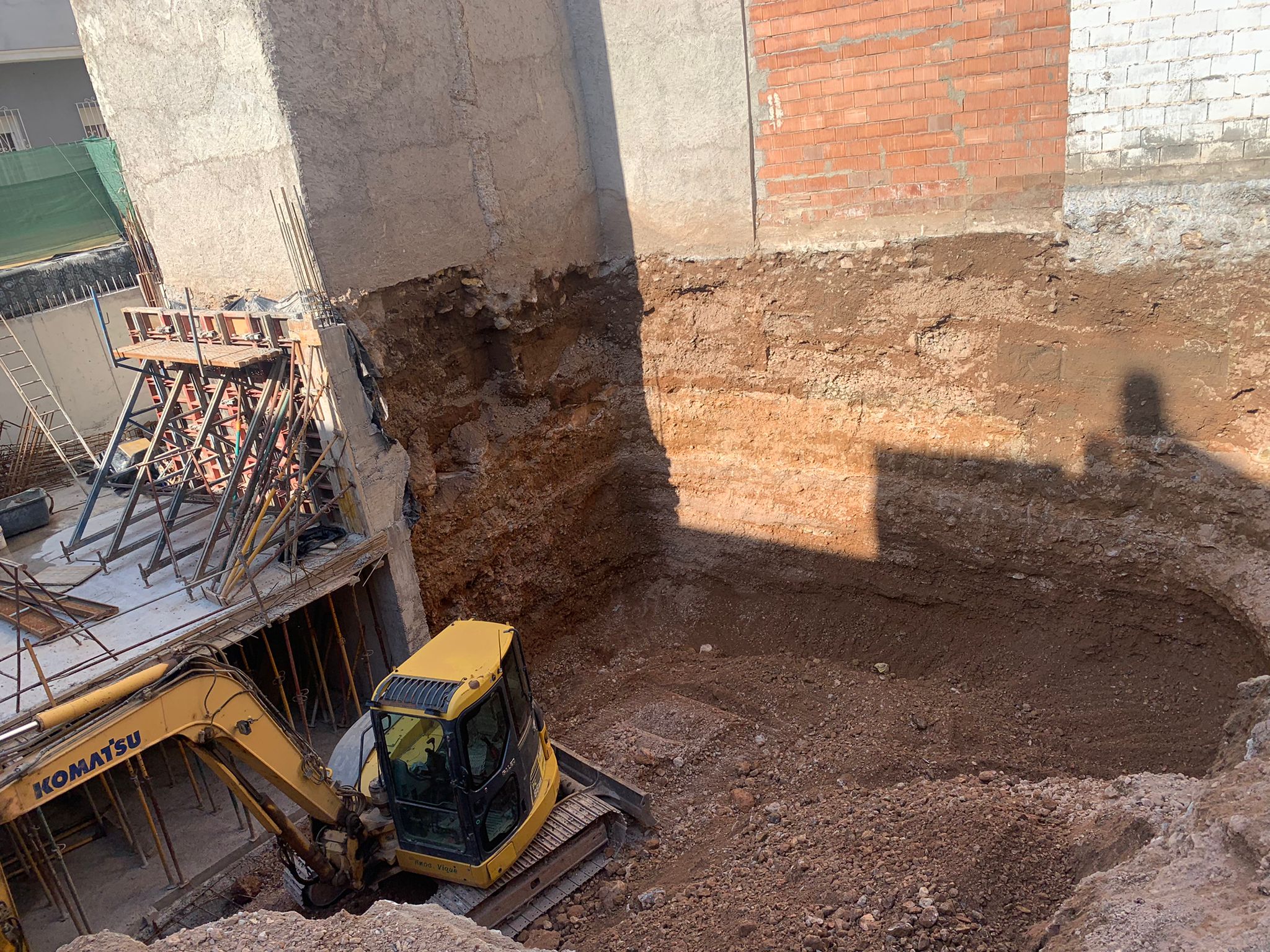 Vista de la excavadora junto a estructura de hormigón en construcción con apuntalamientos