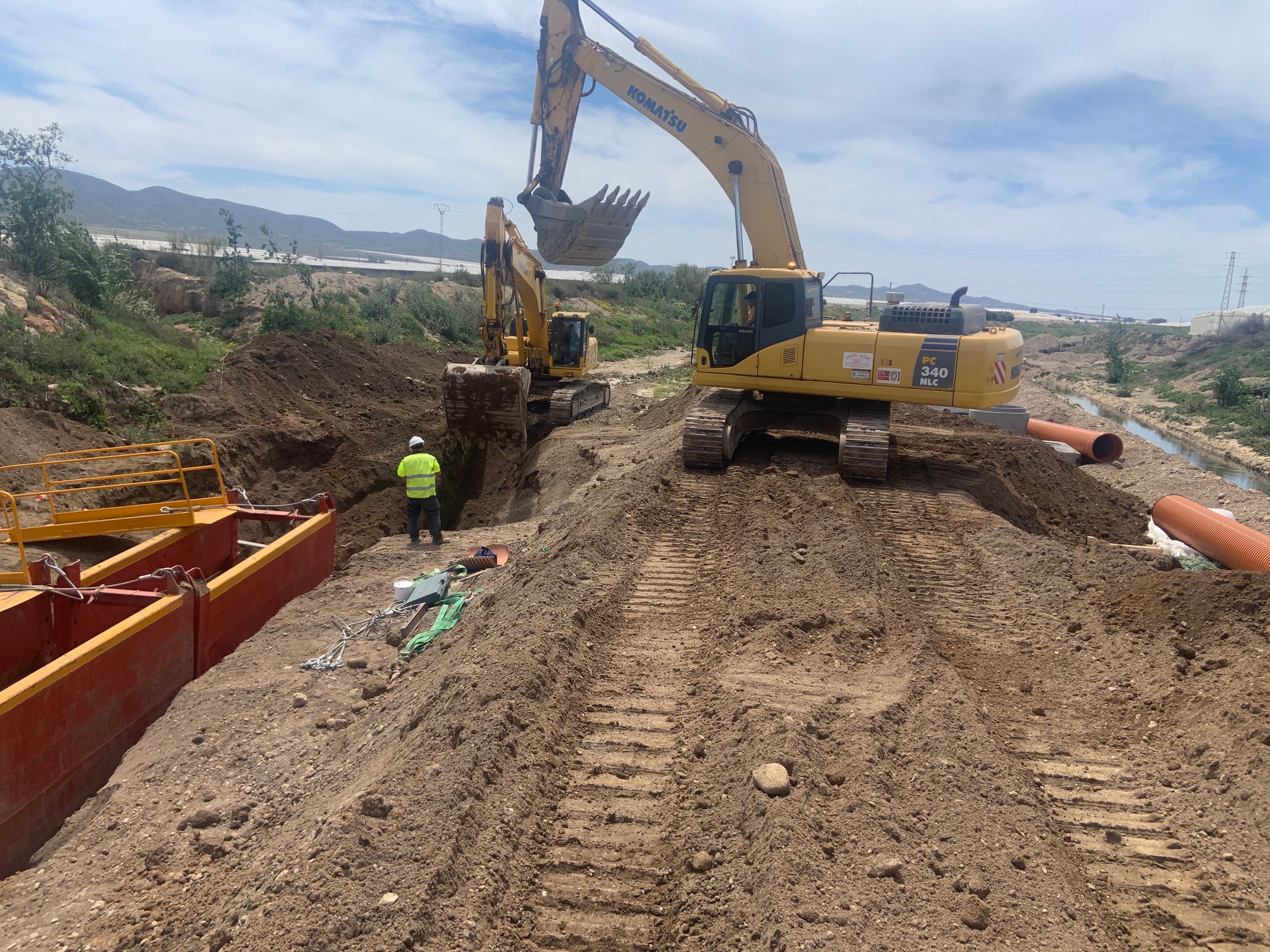 Excavadoras Komatsu PC340 y trabajador supervisando la instalación de tuberías