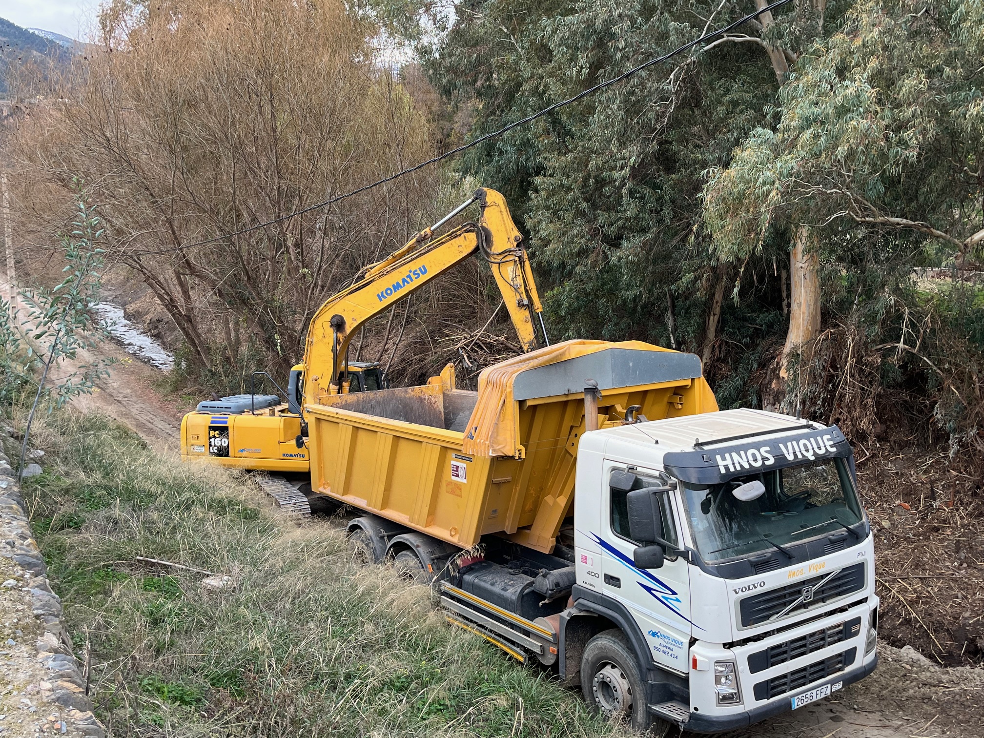 Excavadora cargando material en camión durante los trabajos de limpieza