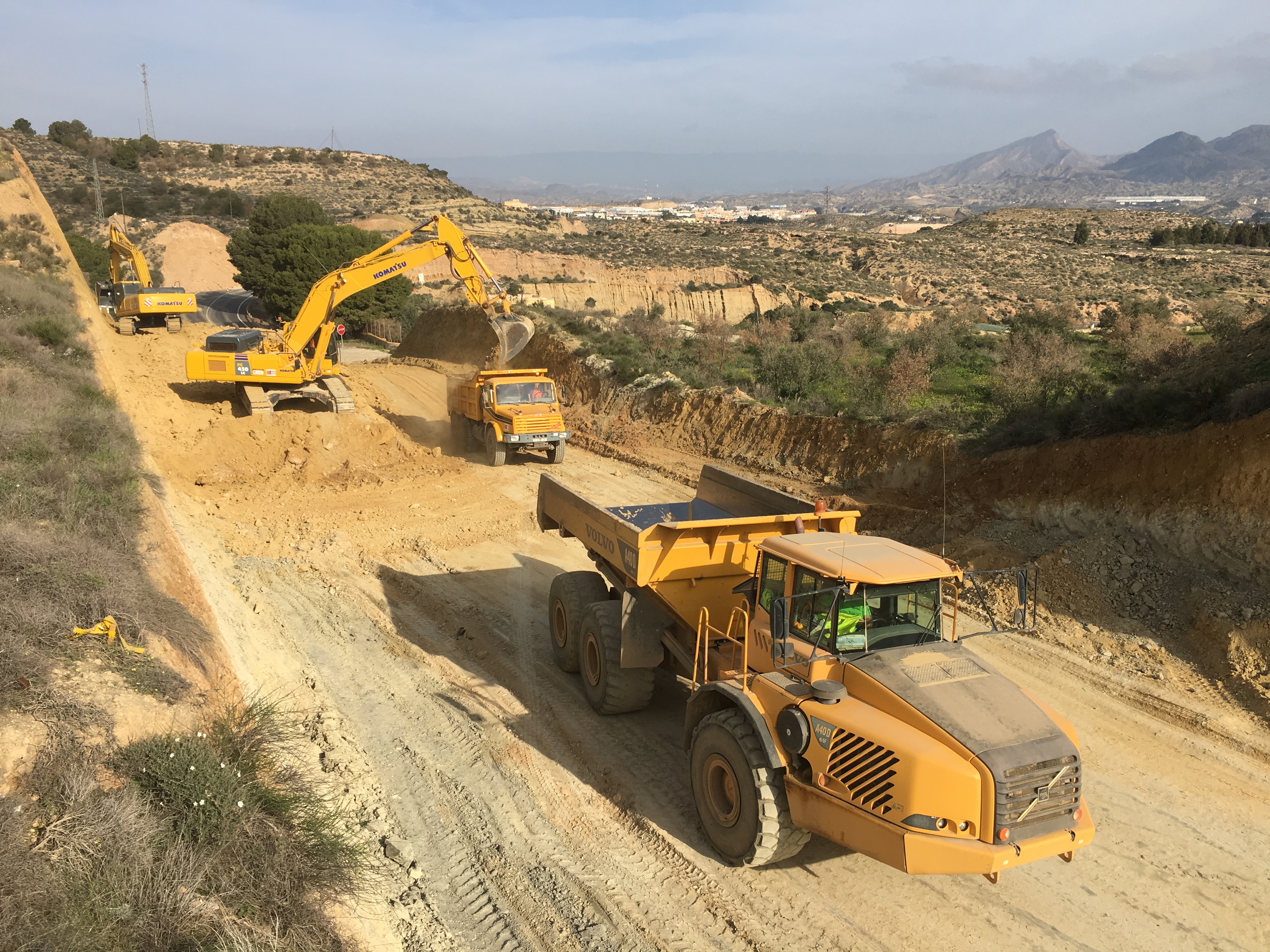 Vista panorámica de la obra con camiones volquete y excavadoras